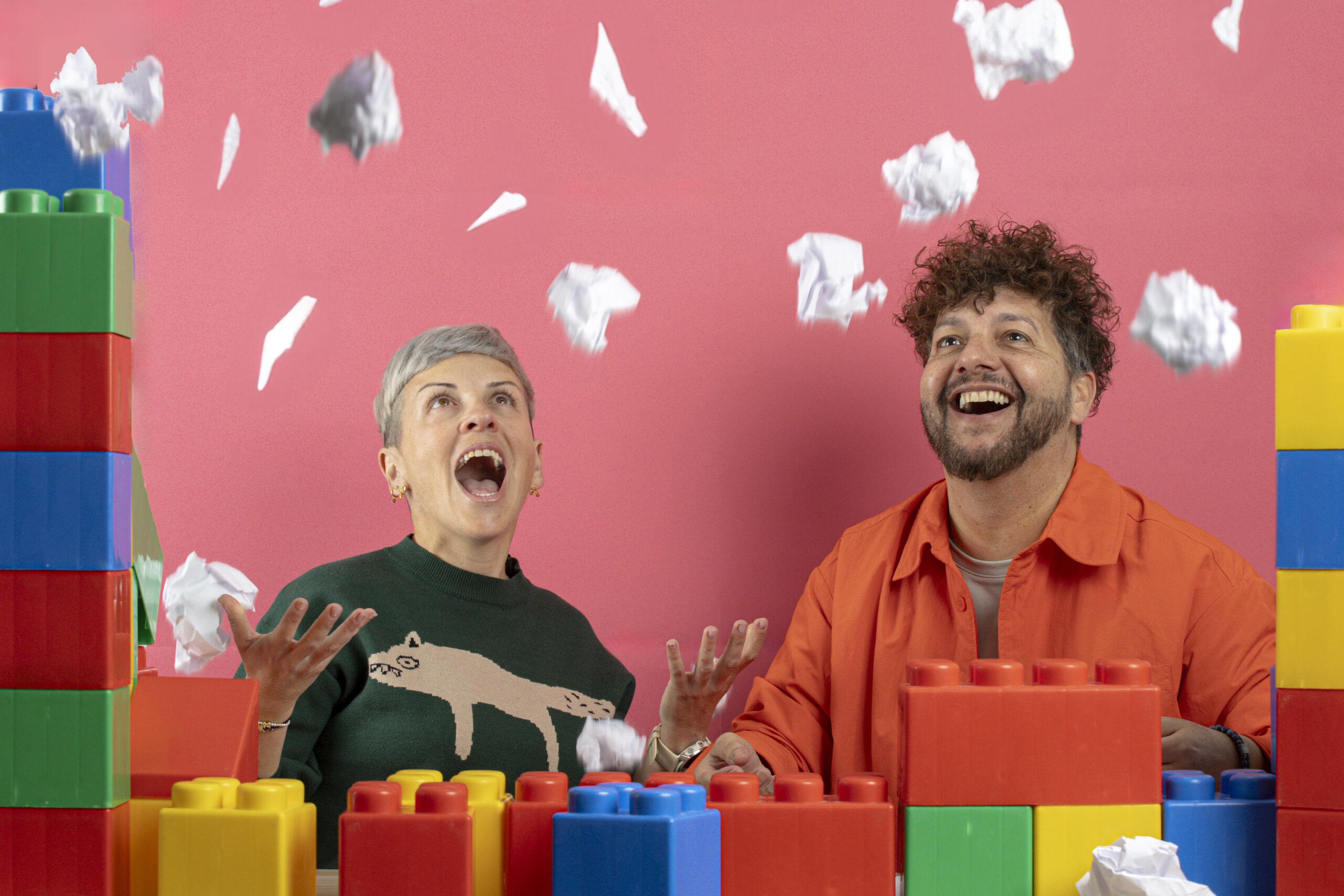 Dos adultos con un juego de bloques de plastico de colores, lanzando papeles al aire y representando una evaluación de síntomas de tdah en adultos